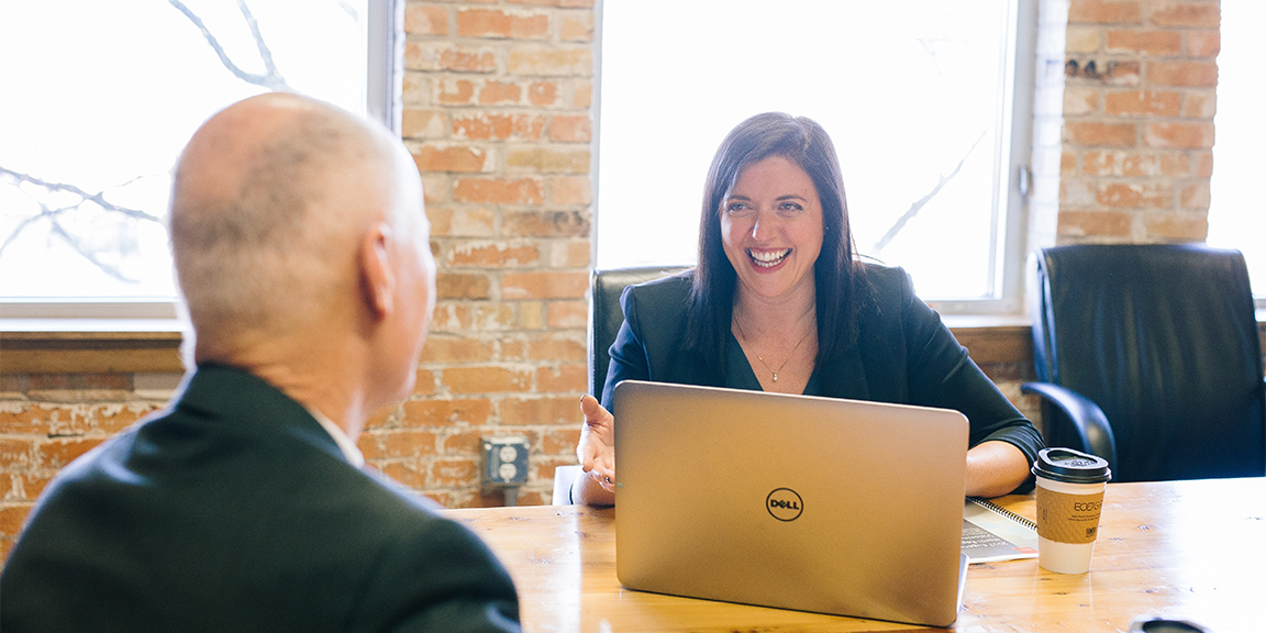 two people in business setting sitting at boardroom table